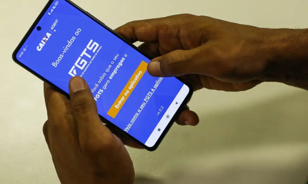 Trabalhador consultando saldo do FGTS no celular para planejar pagamento de dívidas e organização financeira.