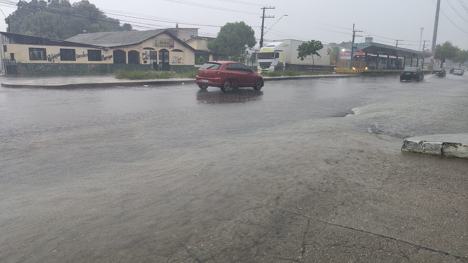 Céu nublado e chuva forte atingindo área urbana no estado do Amazonas sob alerta meteorológico da Defesa Civil.