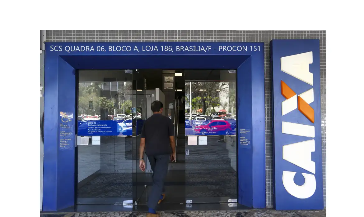 Fachada de agência bancária com portas de vidro fechadas indicando suspensão do atendimento presencial durante o feriado nacional.