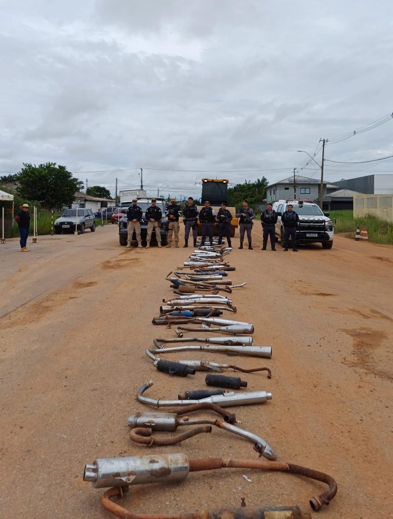 Rolo compactador destruindo escapamentos de motos adulterados em via pública de Humaitá durante operação do Detran-AM