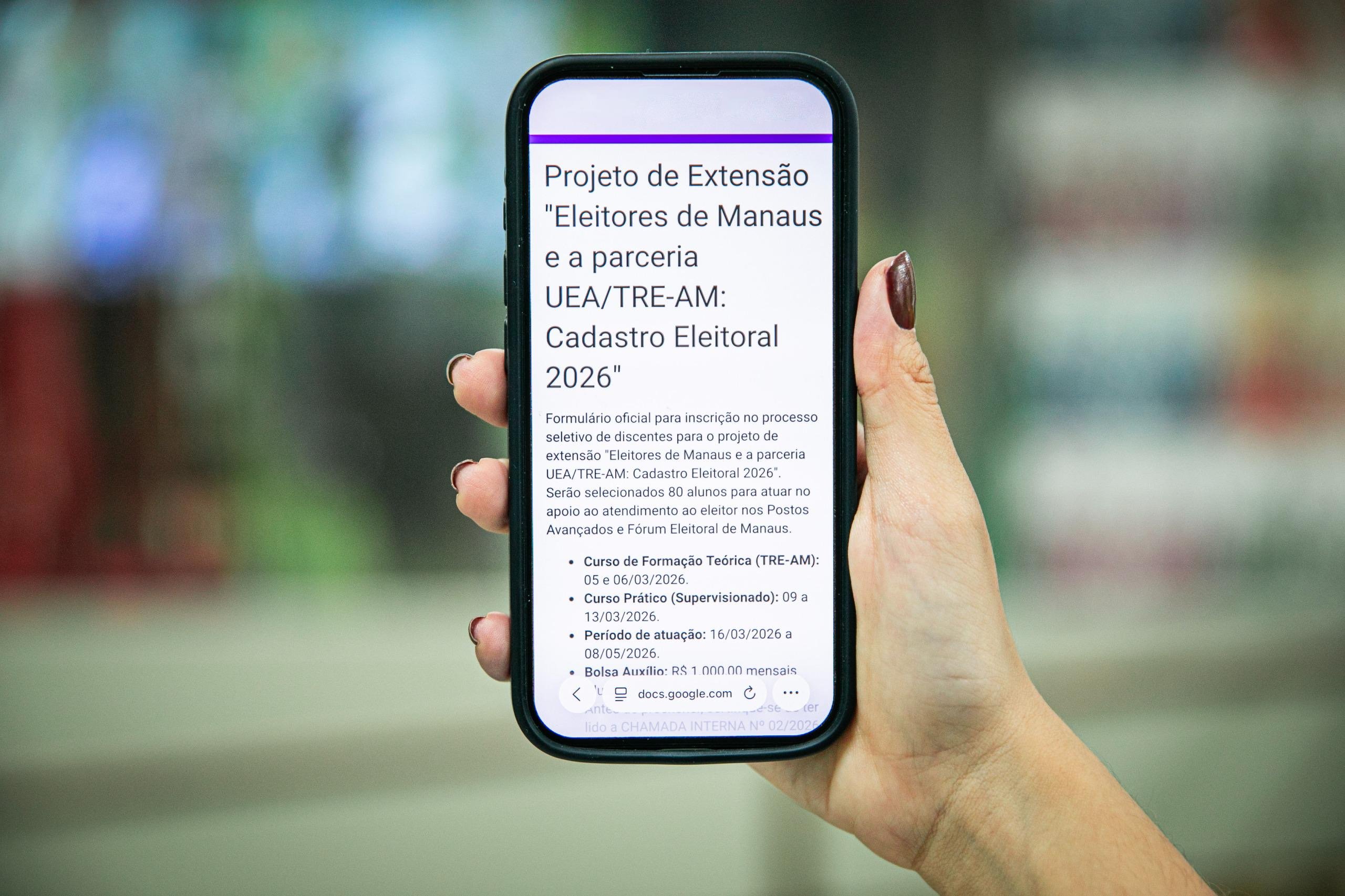 Logotipos da UEA e do TRE-AM em destaque sobre fundo de atendimento eleitoral