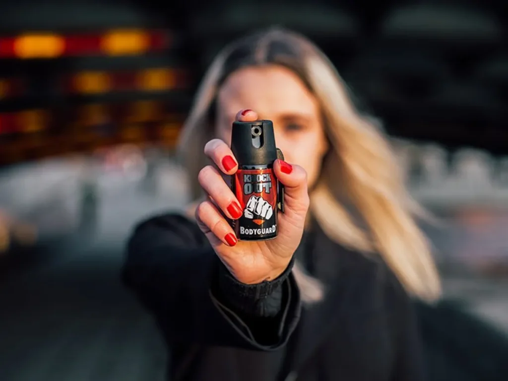 Mulher segurando frasco de spray de pimenta para autodefesa e proteção pessoal.