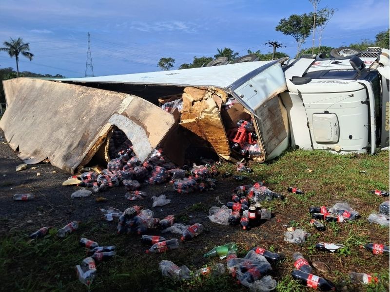 Caminhão de refrigerantes tombado na lateral da rodovia AM-010 com carga espalhada na pista