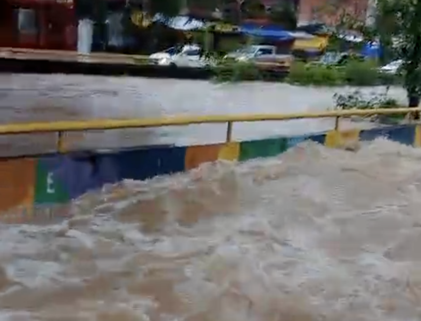 Igarapé transbordando no bairro Compensa em Manaus durante chuva forte atingindo ruas e calçadas