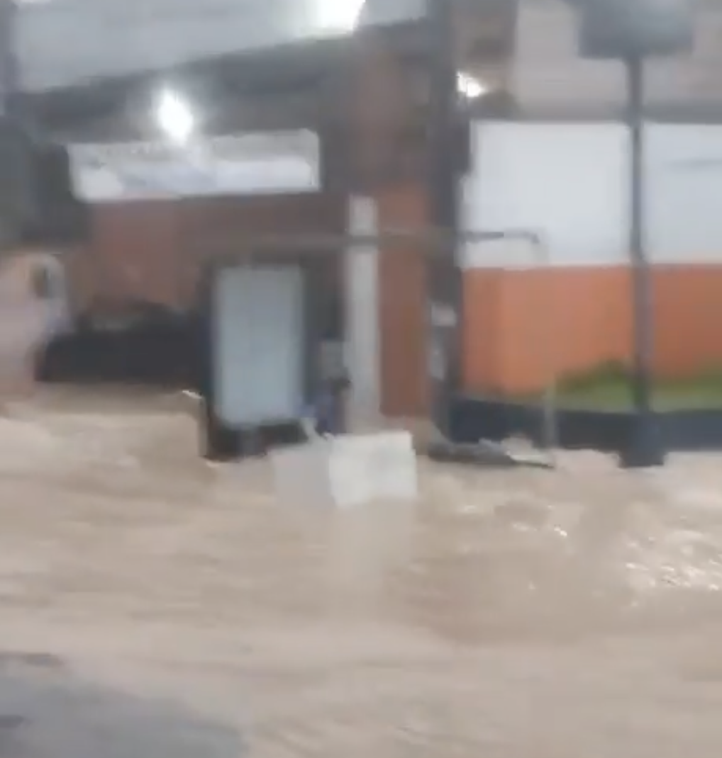 Homem usa geladeira para atravessar avenida alagada durante forte chuva no bairro Compensa em Manaus.