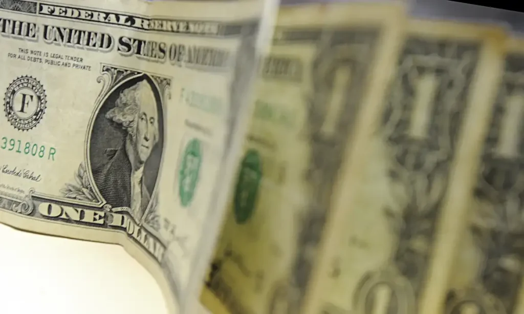 cédulas de dólar e monitor com gráfico da bolsa de valores