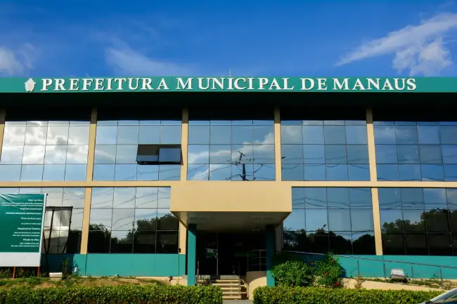 Prédio da Prefeitura de Manaus com as bandeiras oficiais e logomarca da gestão municipal.