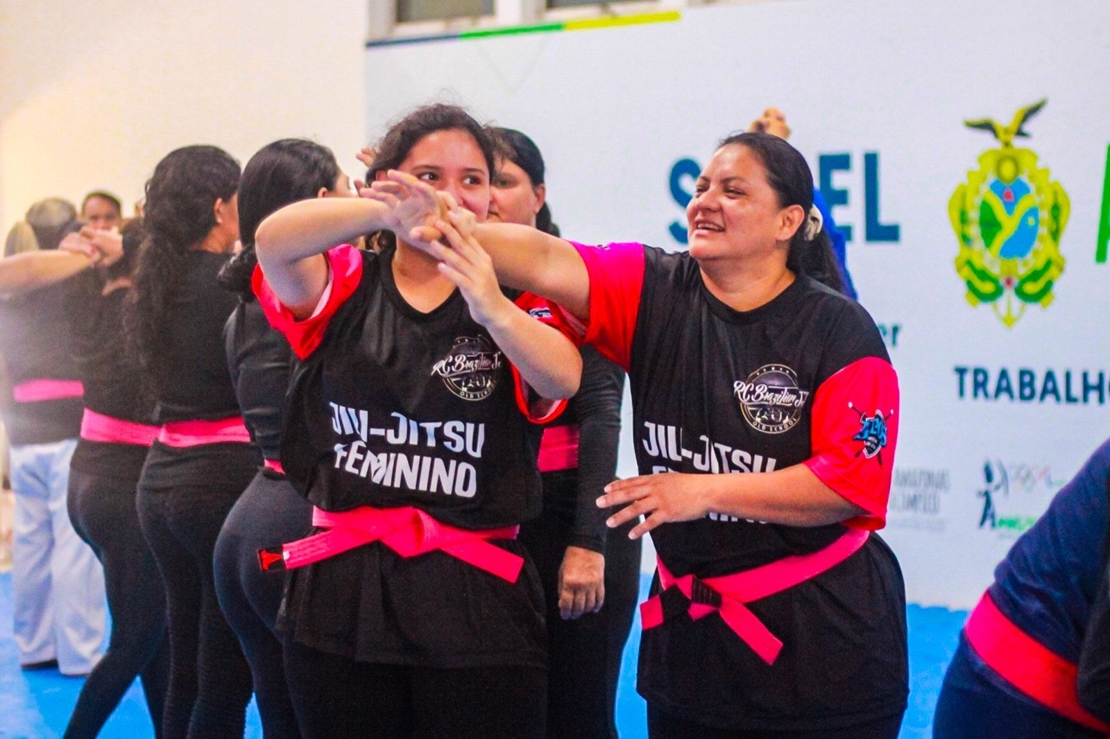 Mulheres reunidas participando de aula inaugural do curso de defesa pessoal feminina em ginásio no interior do Amazonas.