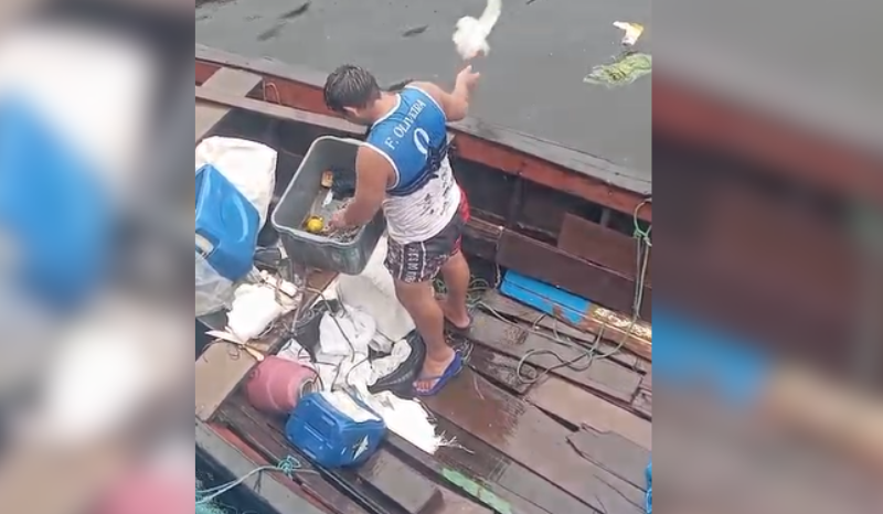 Homem arremessando sacos de lixo nas águas do Rio Negro na região da Manaus Moderna no centro de Manaus
