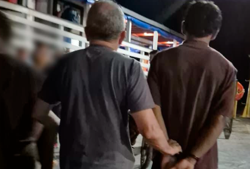 Policial conduzindo homem preso em flagrante com motocicleta recuperada dentro de embarcação no Amazonas