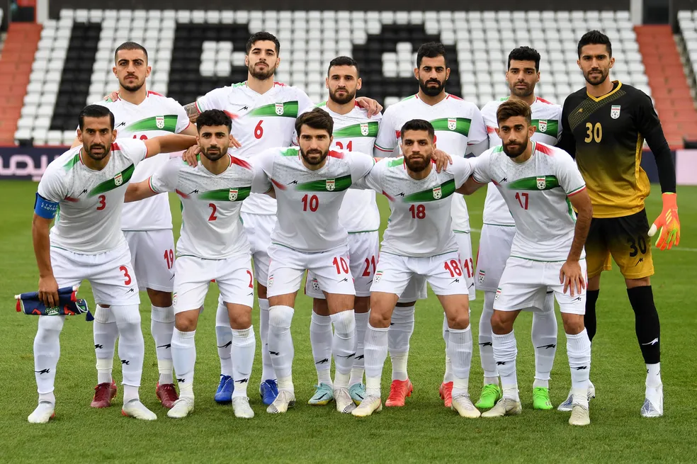 Jogadores da seleção de futebol do Irã perfilados em campo.