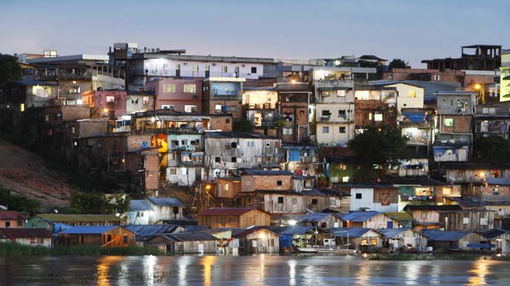 Vista aérea de área urbana com crescimento de comunidades e favelas em Manaus destacando os desafios sociais e de infraestrutura.