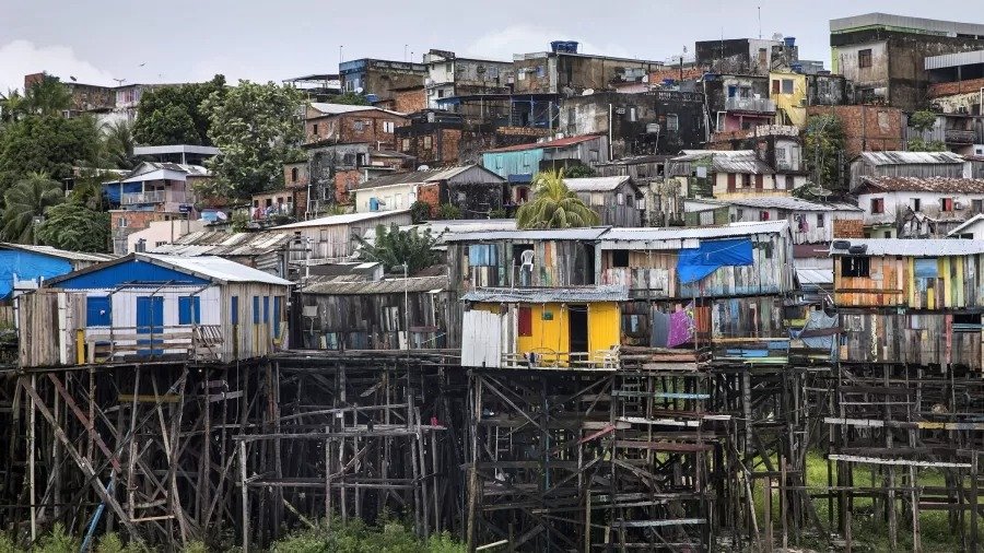 Vista aérea de área urbana com crescimento de comunidades e favelas em Manaus destacando os desafios sociais e de infraestrutura.