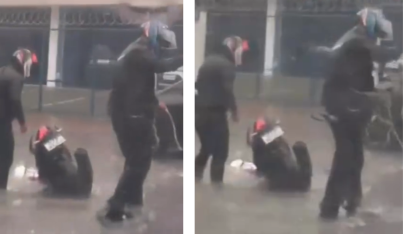 Motociclista tentando retirar motocicleta de buraco coberto por água em rua de Manaus durante chuva.