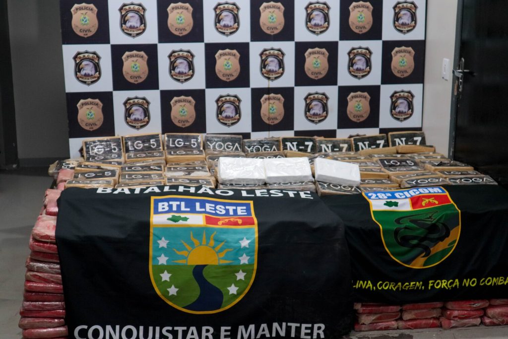 Policiais militares do Amazonas ao lado de grandes fardos de drogas apreendidas durante operação policial no interior do estado.