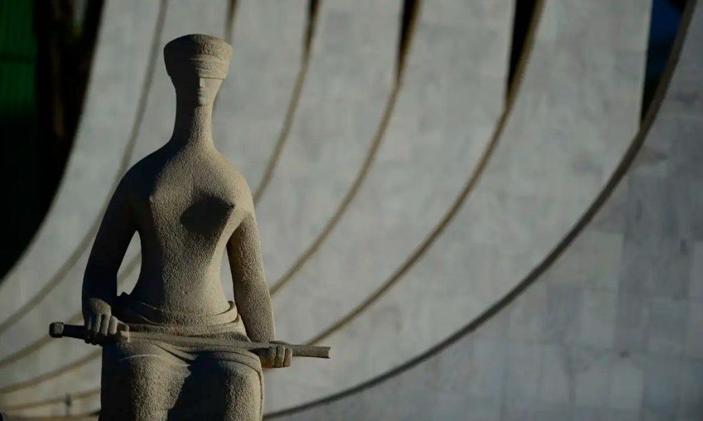 Vista externa do edifício do Supremo Tribunal Federal em Brasília com a escultura da Justiça em destaque na frente.