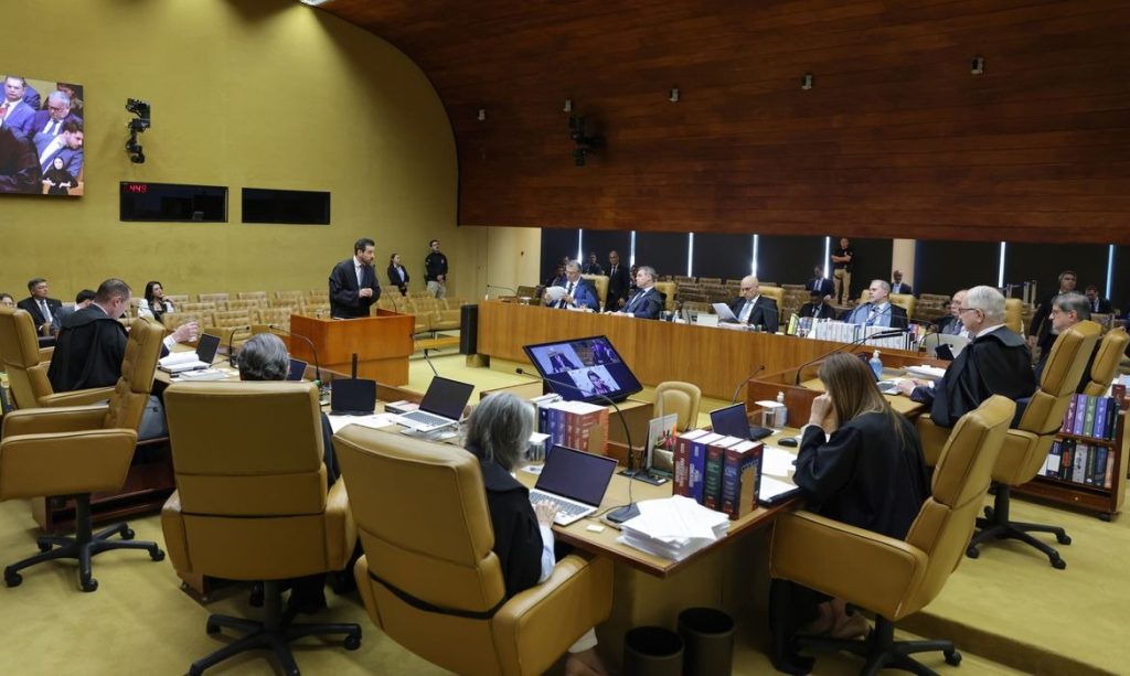 Vista externa do prédio do Supremo Tribunal Federal em Brasília com a bandeira do Brasil em destaque no gramado.