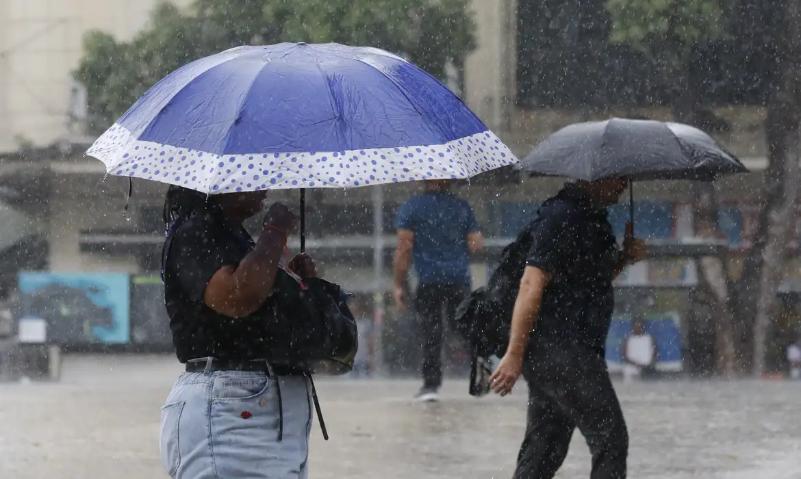 Rua em Manaus sob forte chuva com pontos de alagamento e monitoramento da defesa civil em áreas urbanas de risco