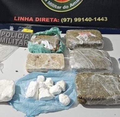 Policiais civis e militares posam ao lado de tabletes de maconha e cocaína apreendidos em delegacia no interior do Amazonas.