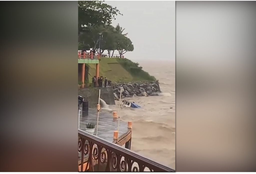 Embarcação de pequeno porte afundando parcialmente na orla de Parintins durante forte temporal no Amazonas.