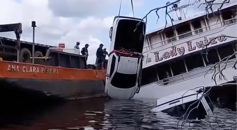 Veículos sendo retirados de ferryboat parcialmente submerso nas águas do Rio Negro no Amazonas.
