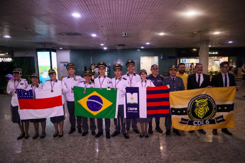 Estudantes medalhistas do Amazonas sendo recebidos com festa no Aeroporto de Manaus após competição na Tailândia.