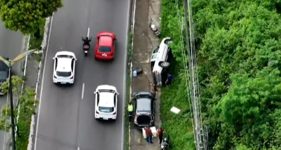 Veículo capotado na calçada da Avenida Rodrigo Otávio em Manaus com trânsito lento ao fundo