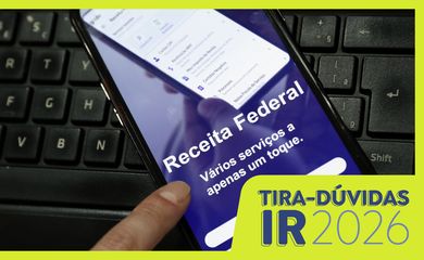 Pessoa utilizando um computador para preencher a declaração do Imposto de Renda 2026 com documentos sobre a mesa.