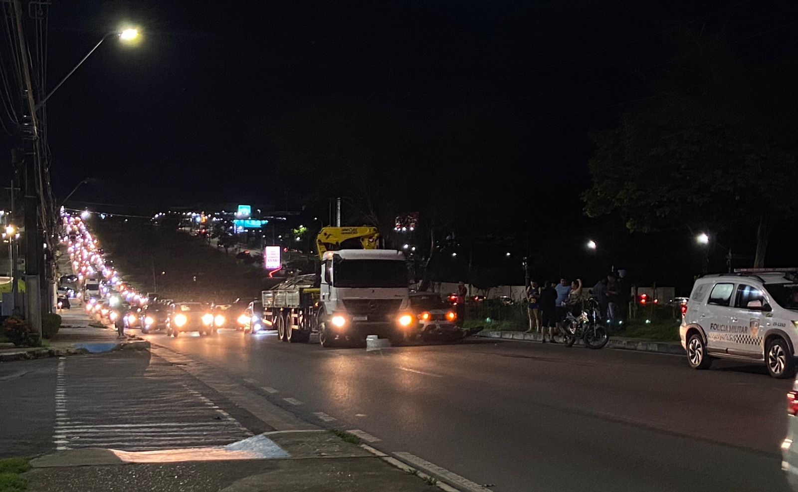 Acidente entre um carro Fiat Mobi e uma motocicleta na Avenida das Torres em Manaus com trânsito congestionado ao fundo.