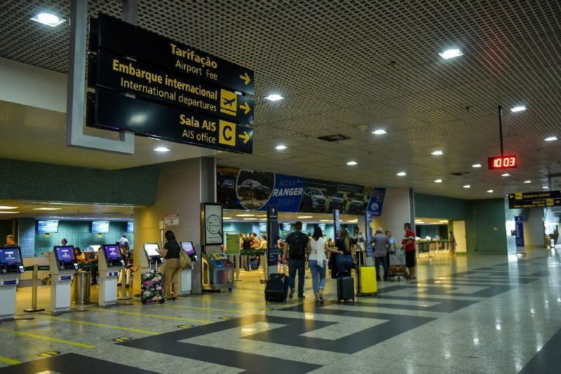 Vista do saguão do Aeroporto Internacional Eduardo Gomes com foco na área de embarque e sinalização de voos.