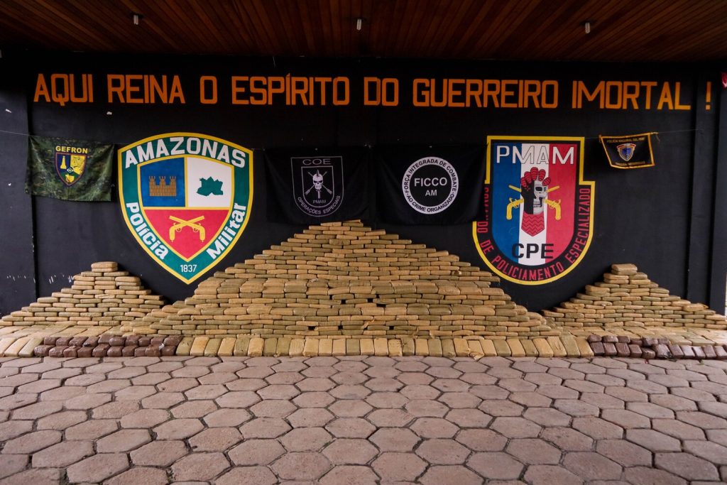 Policiais militares e civis do Amazonas exibem grandes quantidades de drogas e armas apreendidas em operações integradas no estado.