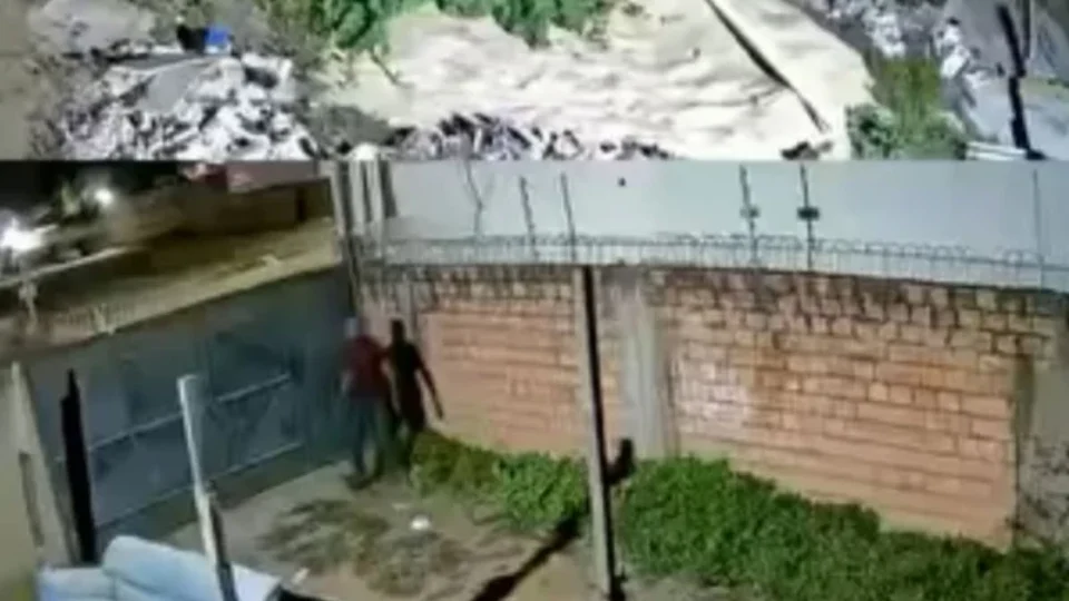 Suspeito pula portão de residência e foge após ser intimidado por voz vinda de câmera de segurança em tempo real.