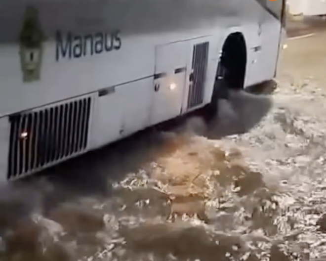 Avenida Getúlio Vargas em Manaus completamente alagada após forte chuva com passageiros ilhados nas paradas de ônibus.