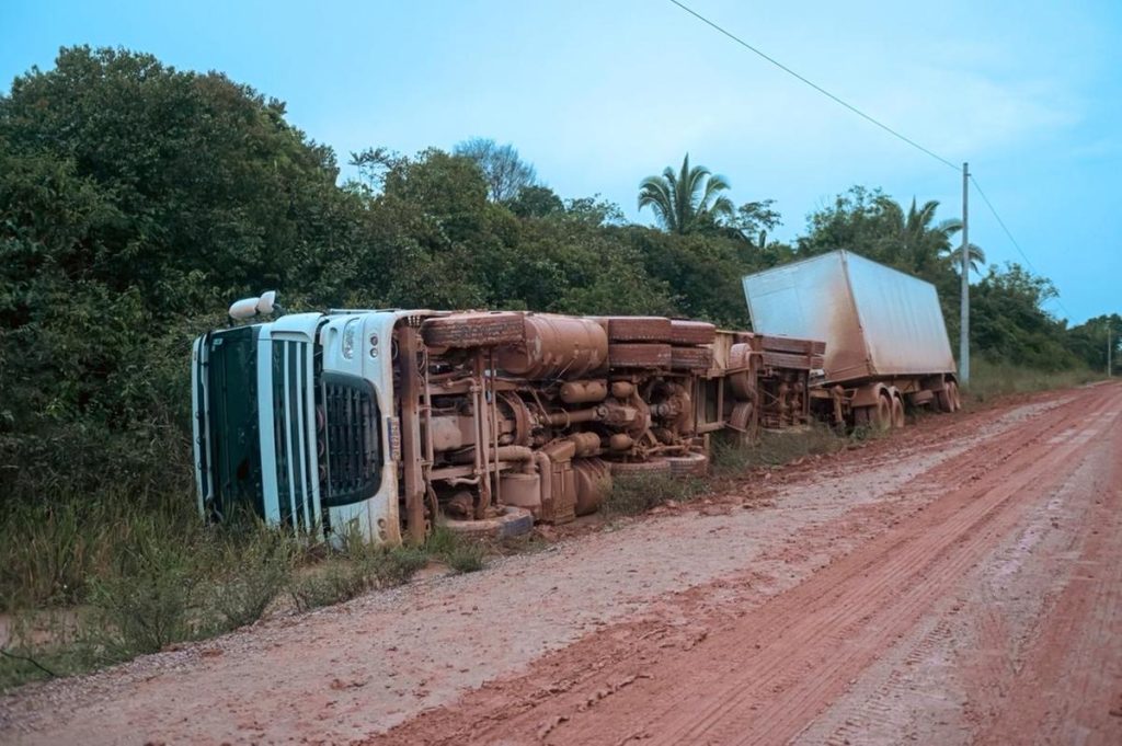 Carreta de 32 toneladas carregada com pneus tombada no acostamento da rodovia BR-319 em trecho de lama.