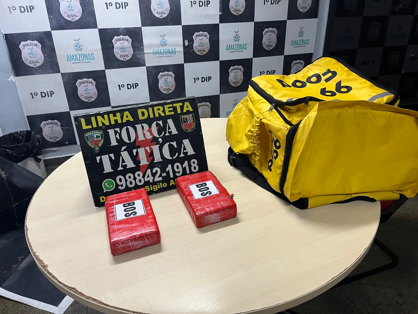 Policiais da Força Tática exibem tabletes de cocaína apreendidos dentro de uma bolsa de entrega de comida em Manaus