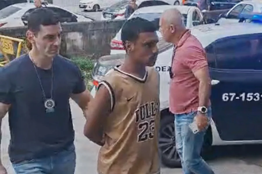 Policiais civis da Delegacia Especial de Apoio ao Turismo conduzem homem preso por aplicar golpe em turista no Rio de Janeiro.