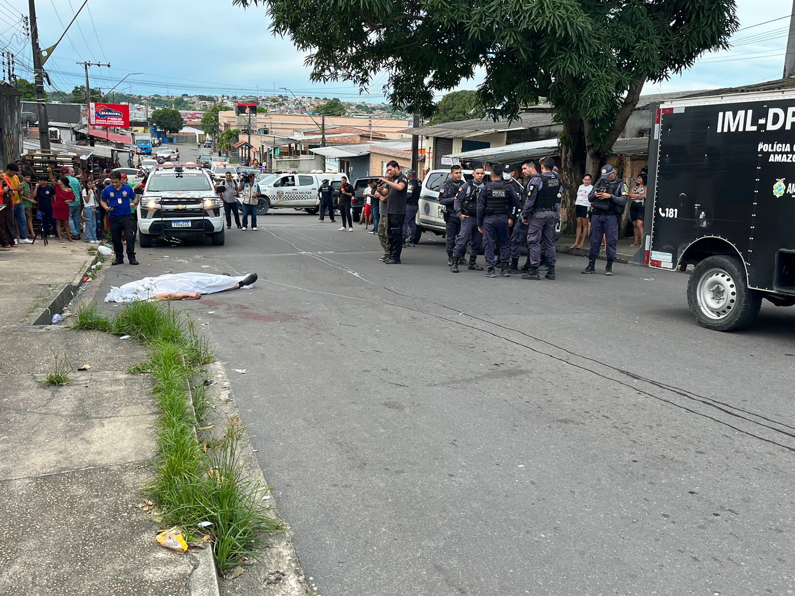 Viatura policial e aglomeração de pessoas no local de homicídio no bairro Jorge Teixeira em Manaus