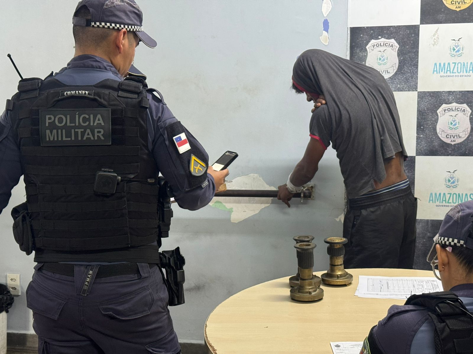 Homem detido por seguranças após furtar peças de hidrante em Manaus sendo conduzido pela polícia militarmente.