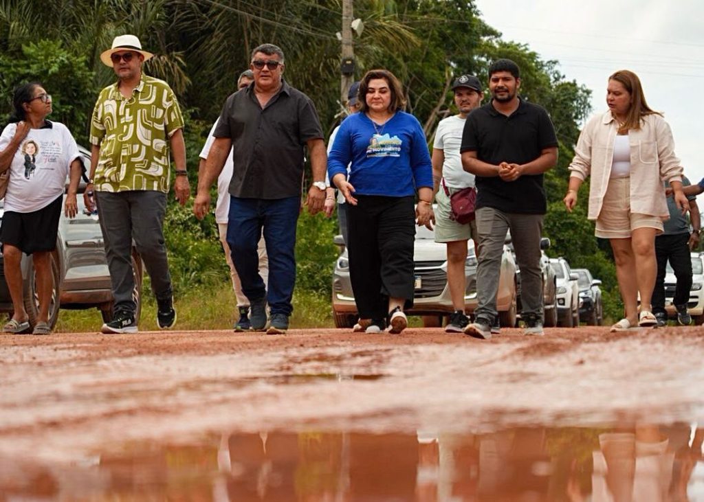 Maria do Carmo caminha por estrada de terra precária no ramal do Janauari em Iranduba acompanhada por lideranças locais.