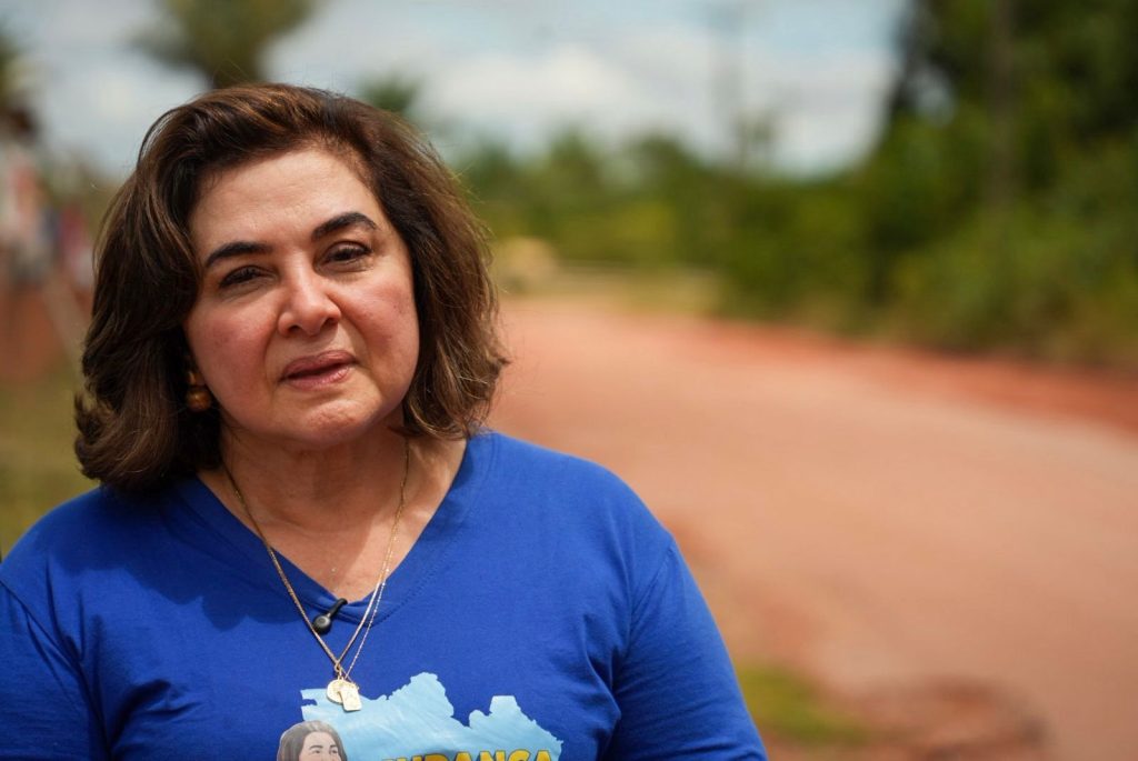 Maria do Carmo caminha por estrada de terra precária no ramal do Janauari em Iranduba acompanhada por lideranças locais.