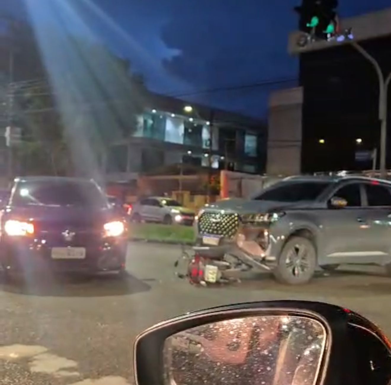 Acidente entre carro e motocicleta na avenida Pedro Teixeira em Manaus com moto presa sob o veículo.