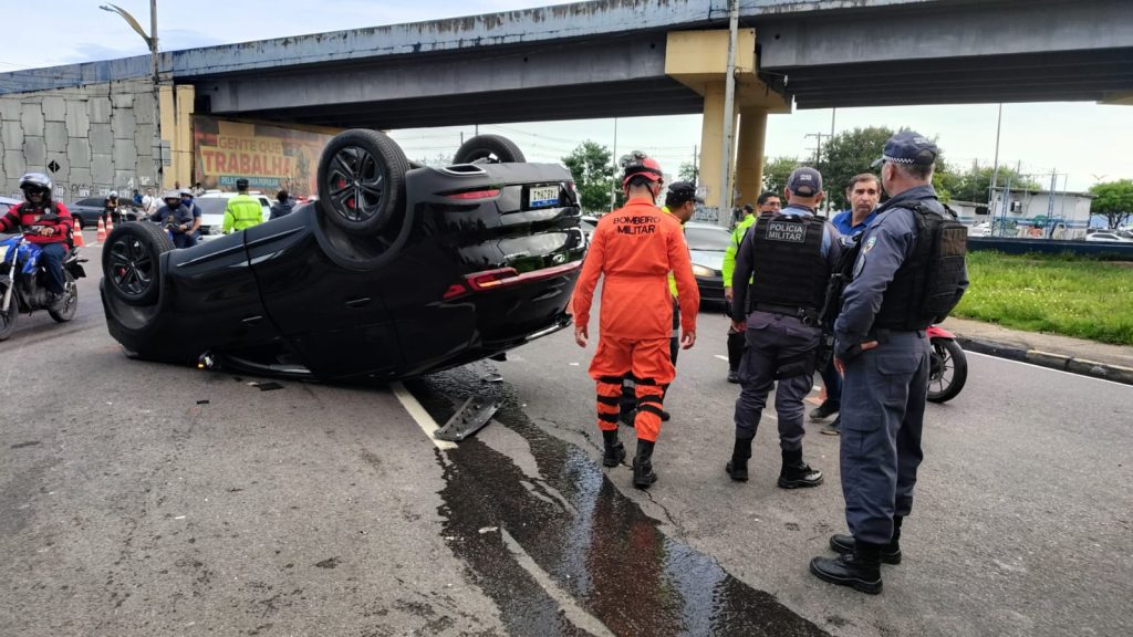 Veículo capotado após acidente grave na rotatória do Coroado em Manaus com mureta de concreto ao fundo.