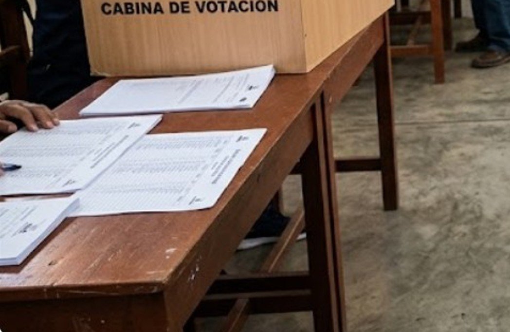 Pessoas votando em seção eleitoral no Peru com urnas e cédulas de papel