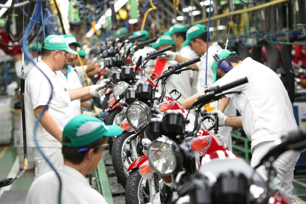 Linha de produção de motocicletas no Polo Industrial de Manaus mostrando trabalhadores e montagem de veículos.
