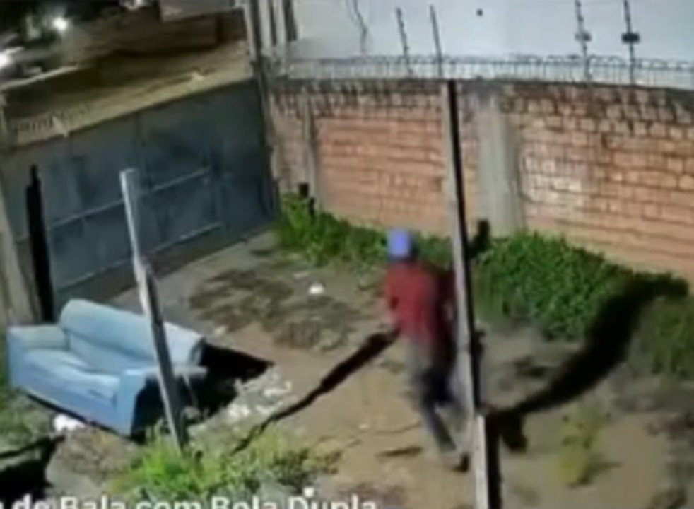 Suspeito pulando portão de residência e fugindo após ser avisado por câmera de segurança com áudio.