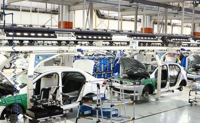 Maquinário de uma linha de produção industrial brasileira destacando o crescimento nos setores automotivo e de derivados de petróleo.