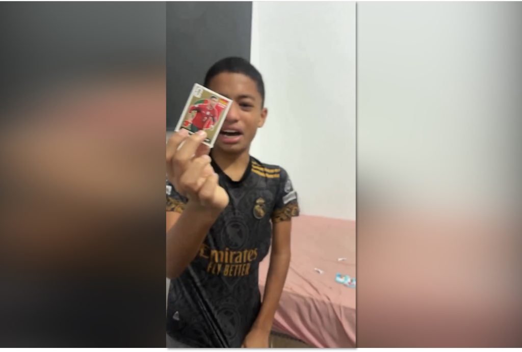 Menino emocionado segurando figurinha rara de cristiano ronaldo