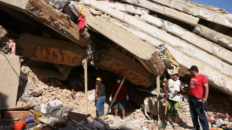 Pessoas trabalham no resgate de vítimas dos escombros de um prédio destruído na venezuela